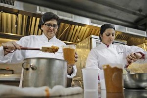Rachana Rimel, left, and Dhuha Jasim package Adas, a lentil dish from Eritrea, in New York, Tuesday, March 29, 2016. A food delivery service is offering New Yorkers the chance to try some food cooked by some unusual chefs. All seven employees at Eat Offbeat are either refugees or asylum-seekers who fled their home countries. They’re cooking foods from those places, including Iraq and Nepal. (AP Photo/Seth Wenig)